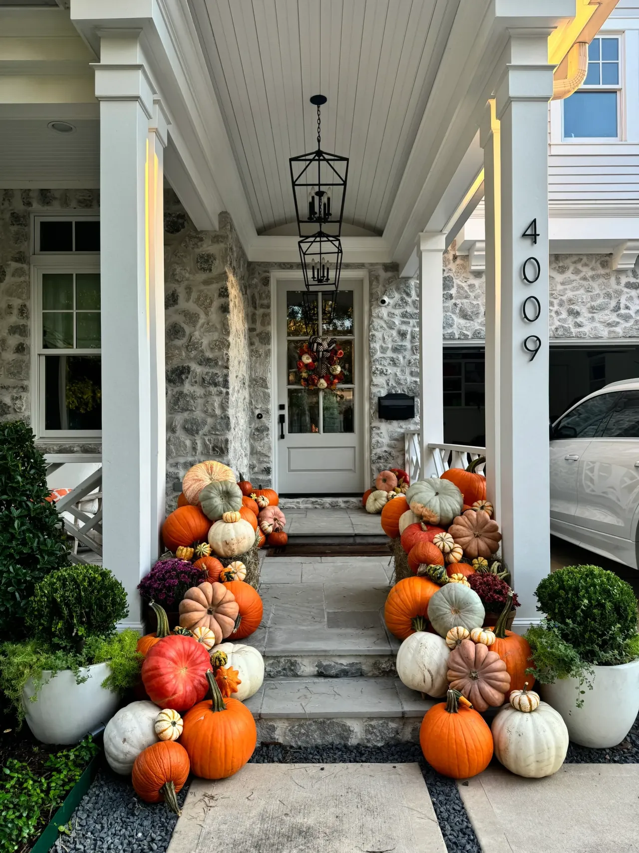 Pumpkins and mums cascading along a stone porch walkway at dusk